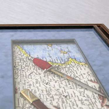 Старинный кинжал и карта в багетной раме под стеклом